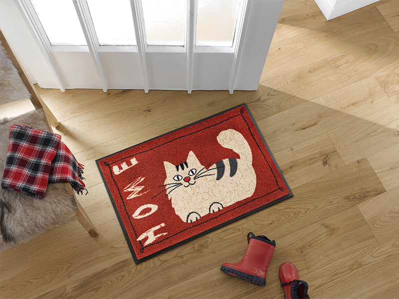 rote Fußmatte mit Katzenmotiv und Schrift "HOME" im Eingangsbereich