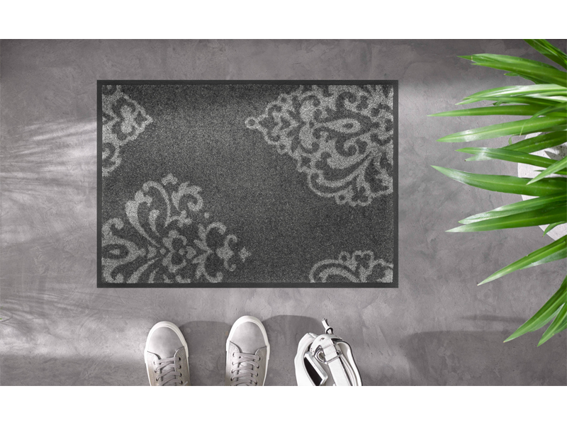dunkelgraue Fußmatte mit hellgrauen Ornamenten auf dem Fußboden