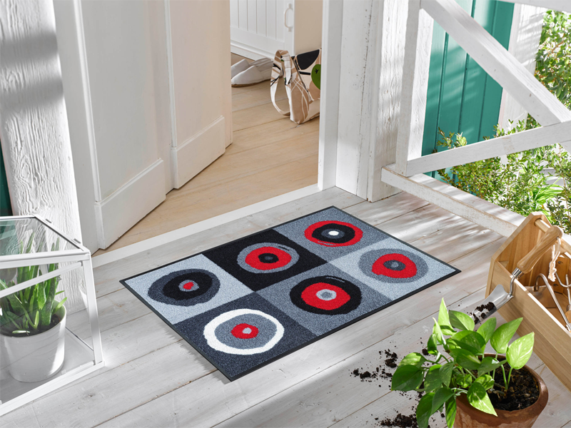 Fußmatte mit runden Kreisen in rot-grauen Farben vor der Eingangstür