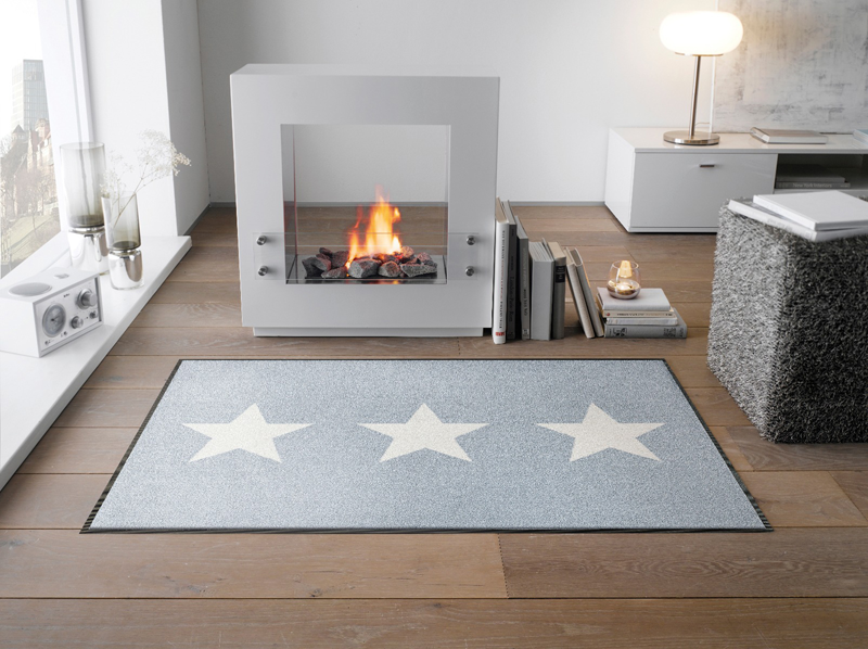 Fußmatte mit drei weißen Sternen auf hellgrauem Hintergrund im Wohnzimmer