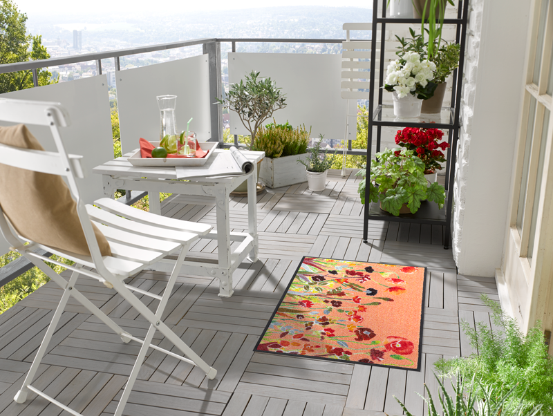 Fußmatte in Rottönen mit farbenfrohen Blumen auf dem Balkon