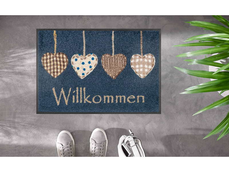 Fußmatte mit Herzen und Schrift "Willkommen" auf dem Fußboden